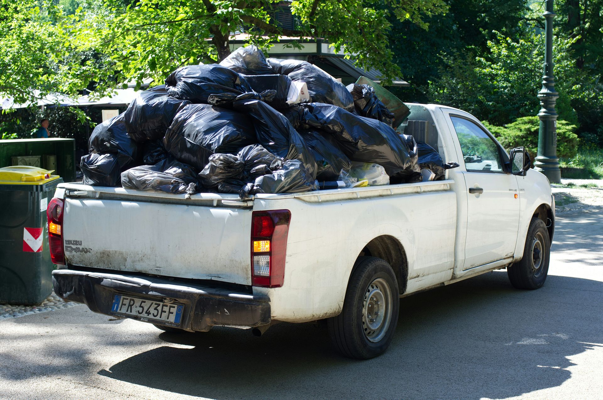 A white pickup truck overloaded with black trash bags